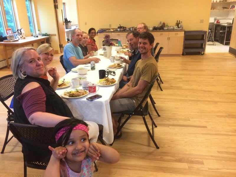 A group of adults and a child eating together at a long table