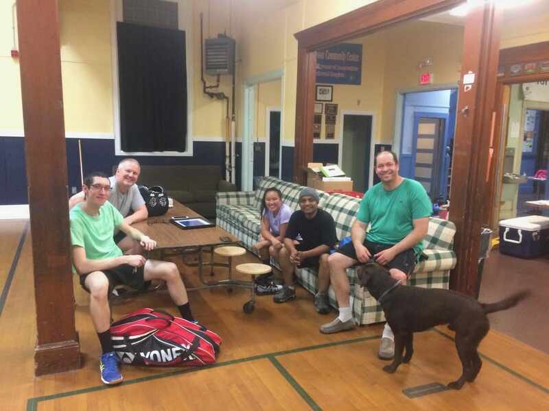 Arasu and his badminton group sitting together after a session, racquet bags on the floor