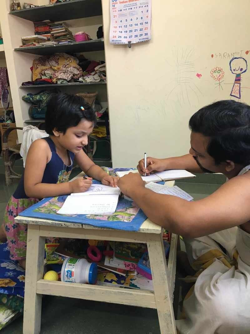 Two people working together over notebooks at a small table